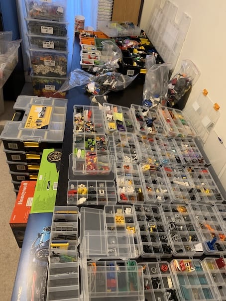 Tables full of LEGO parts in sorting trays and organizers